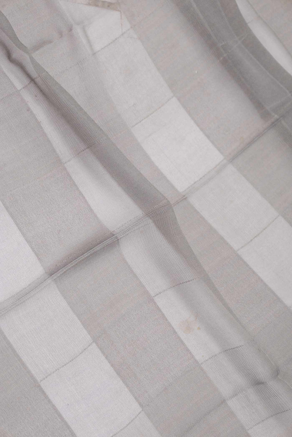 Close up of Grey Dual Tone Mysore Georgette Saree With Printed design on the body and Zari Border displaying folds