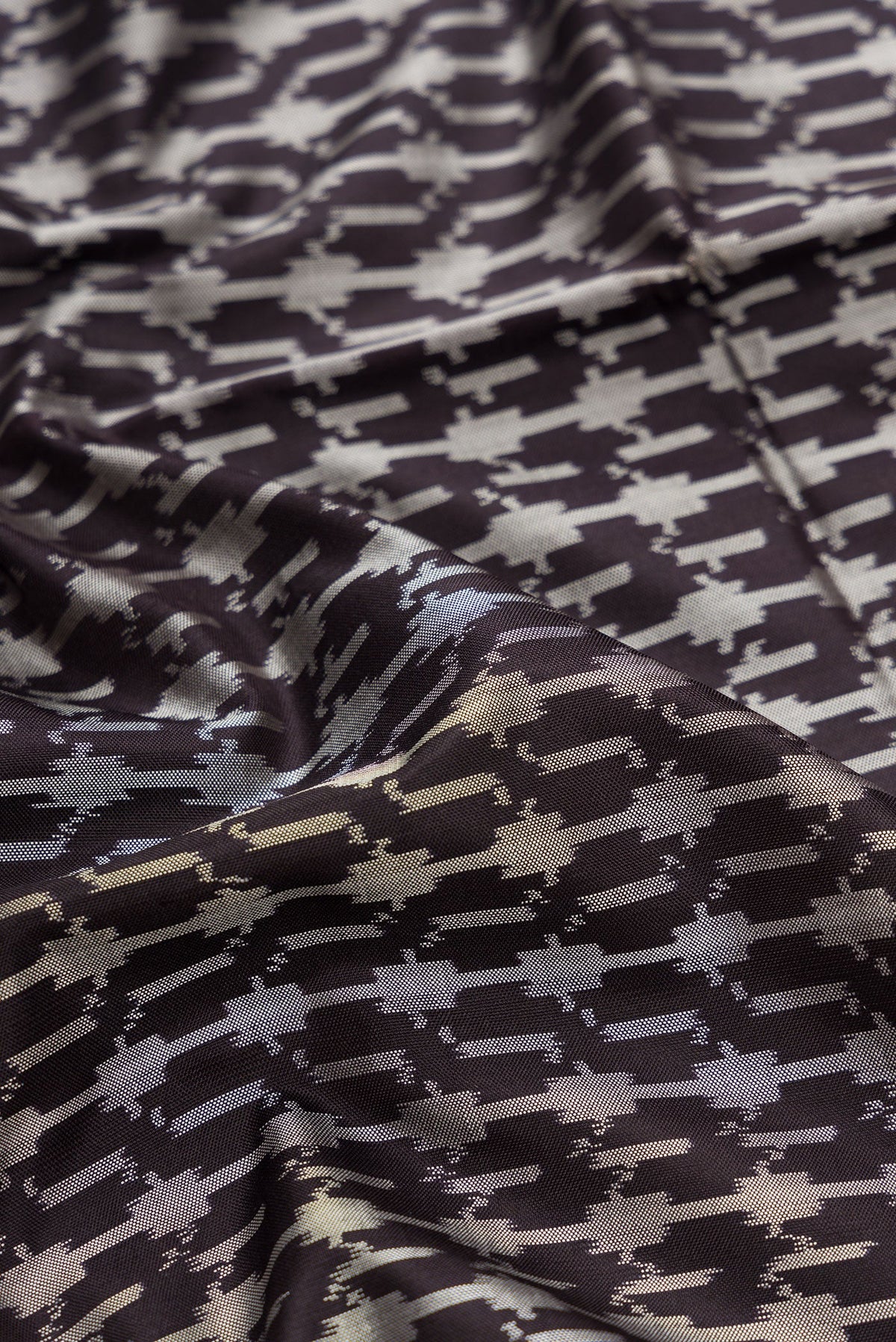 Close up of Black Dual Tone Double Ikat Saree with Ikat Print on the body and Zari Border.  displaying folds
