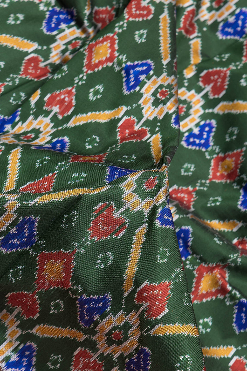 Close up of Bottle Green Dual Tone Kanchipuram Silk Saree with Ikat Print on the body and Zari Border.  displaying folds