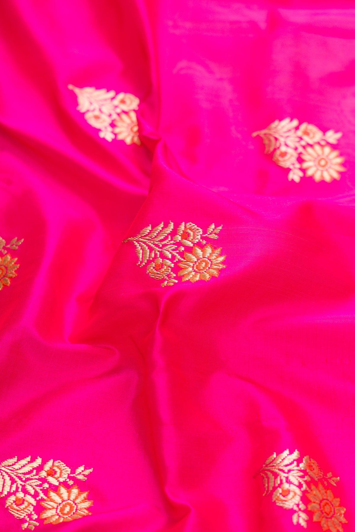 Close up of Pure Silk Pure Zari Pink Dual Tone Banarasi Saree with Zari And Thread Butta on the body and Zari Border displaying folds