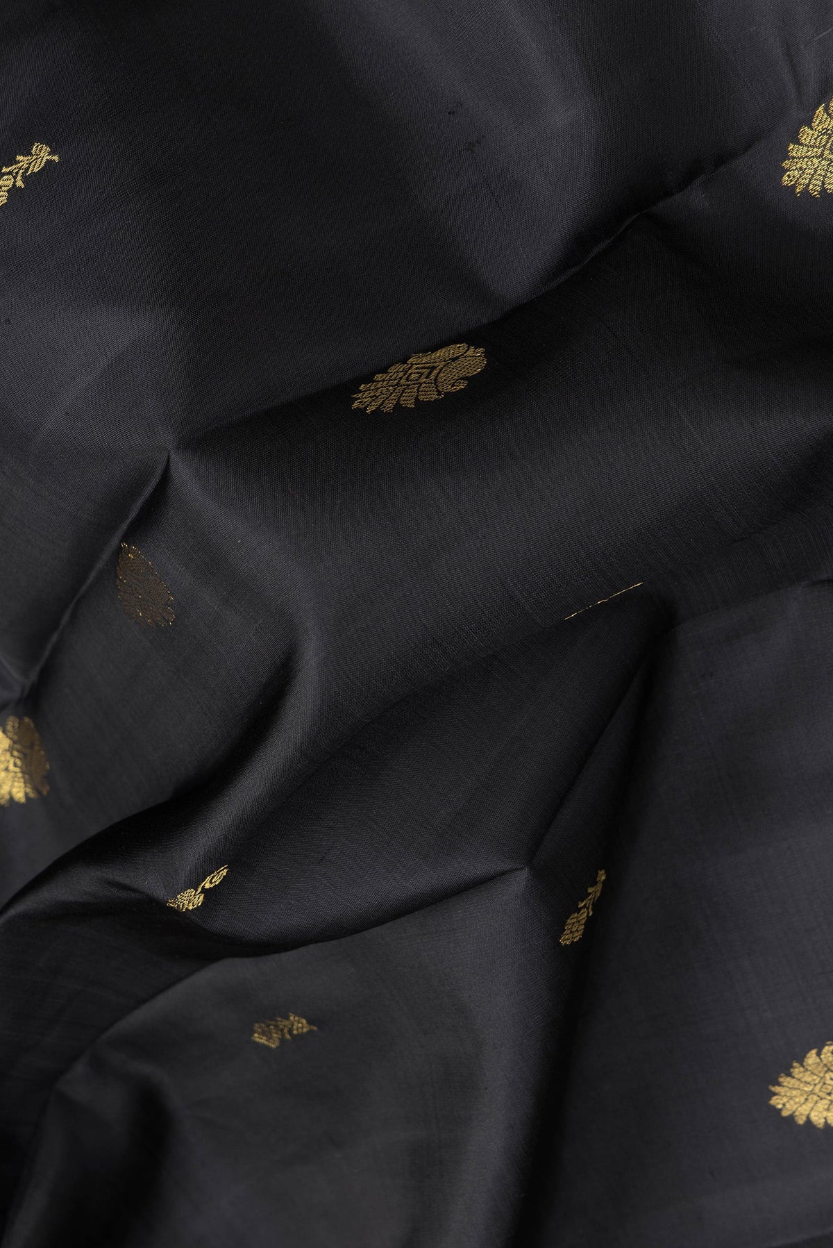 Close up of Black Dual Tone Kanjivaram Silk Saree with Zari Butta on the body and Zari Border.  displaying folds