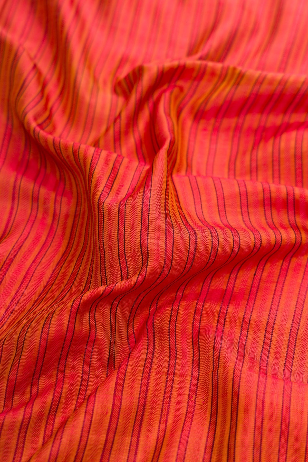 Close up of Red Dual Tone Rajkot Patola Silk Saree with Stripes on the body and Paithani Border.  displaying folds