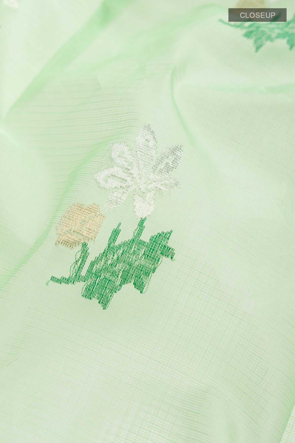 Close up of Green Kota Silk Saree with Zari And Thread Butta on the body and Zari Border displaying folds