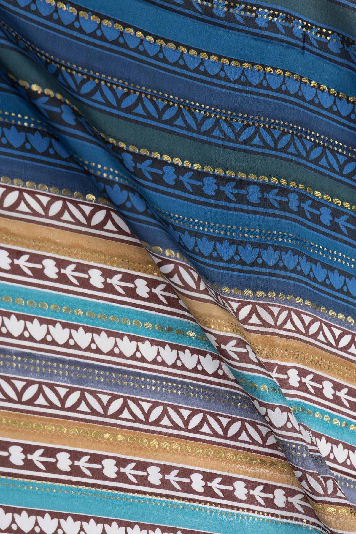 Close up of Blue , Brown and Grey Color Mysore Crepe Saree with Printed design on the body and Zari Border displaying folds
