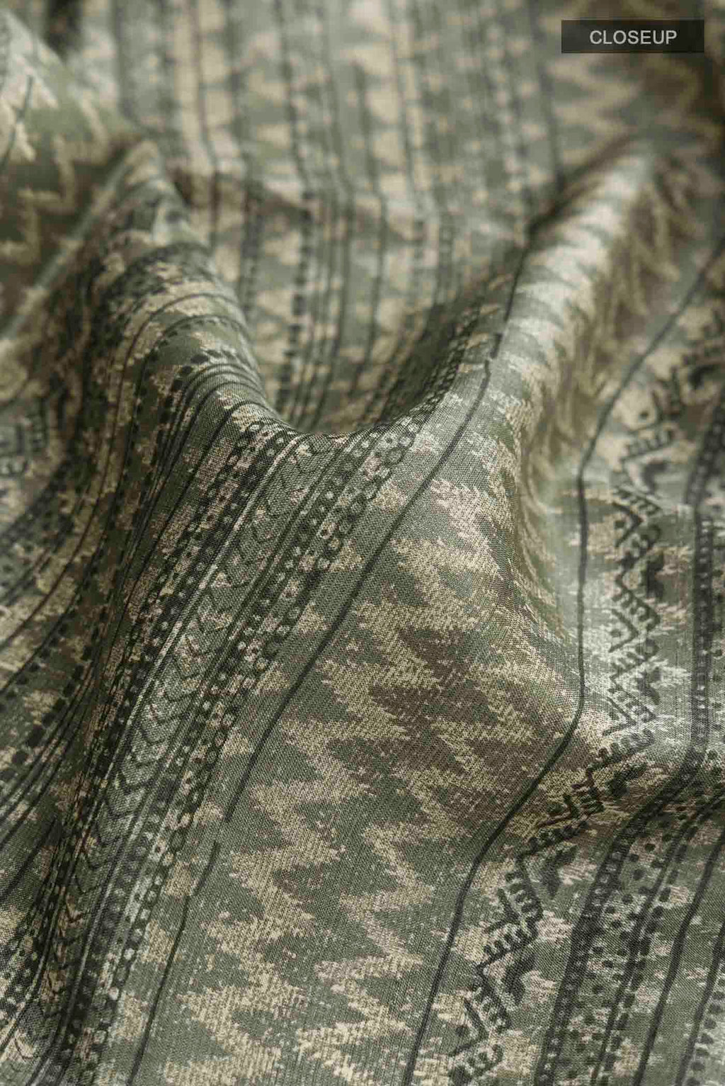 Close up of Green Tussar Silk Saree with Printed design on the body and Plain Border displaying folds