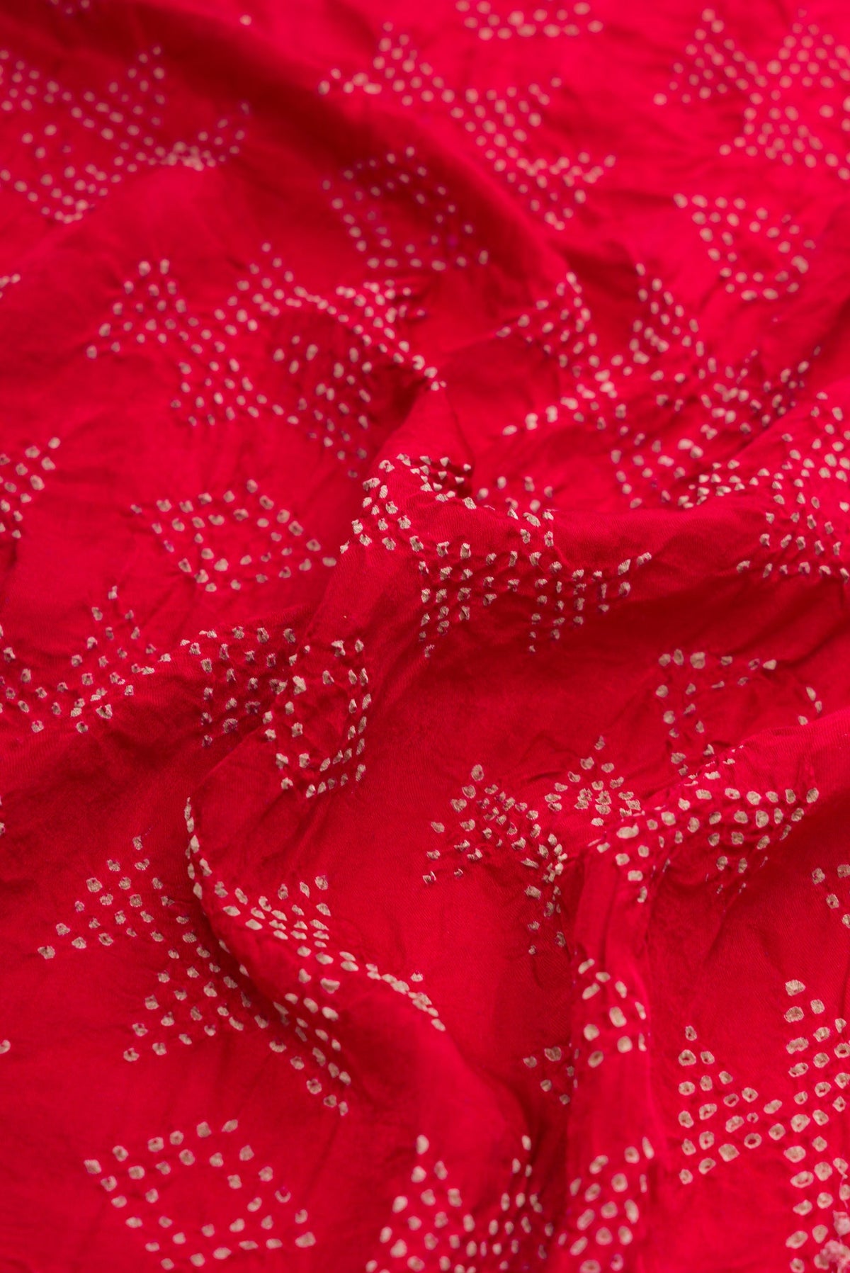 Close up of Red Dual Tone Bandhani Silk Saree with Bandhani Print on the body and Without Border.  displaying folds