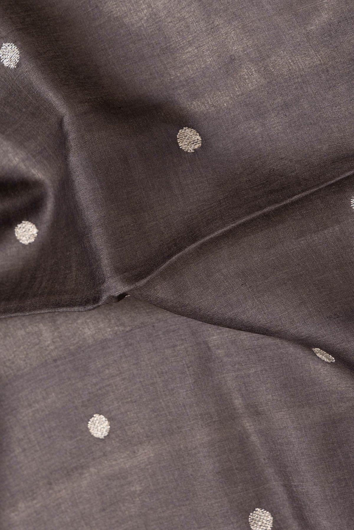 Close up of Brown Dual Tone Tussar Silk Saree with Zari Butta on the body and Embroidery Border.  displaying folds