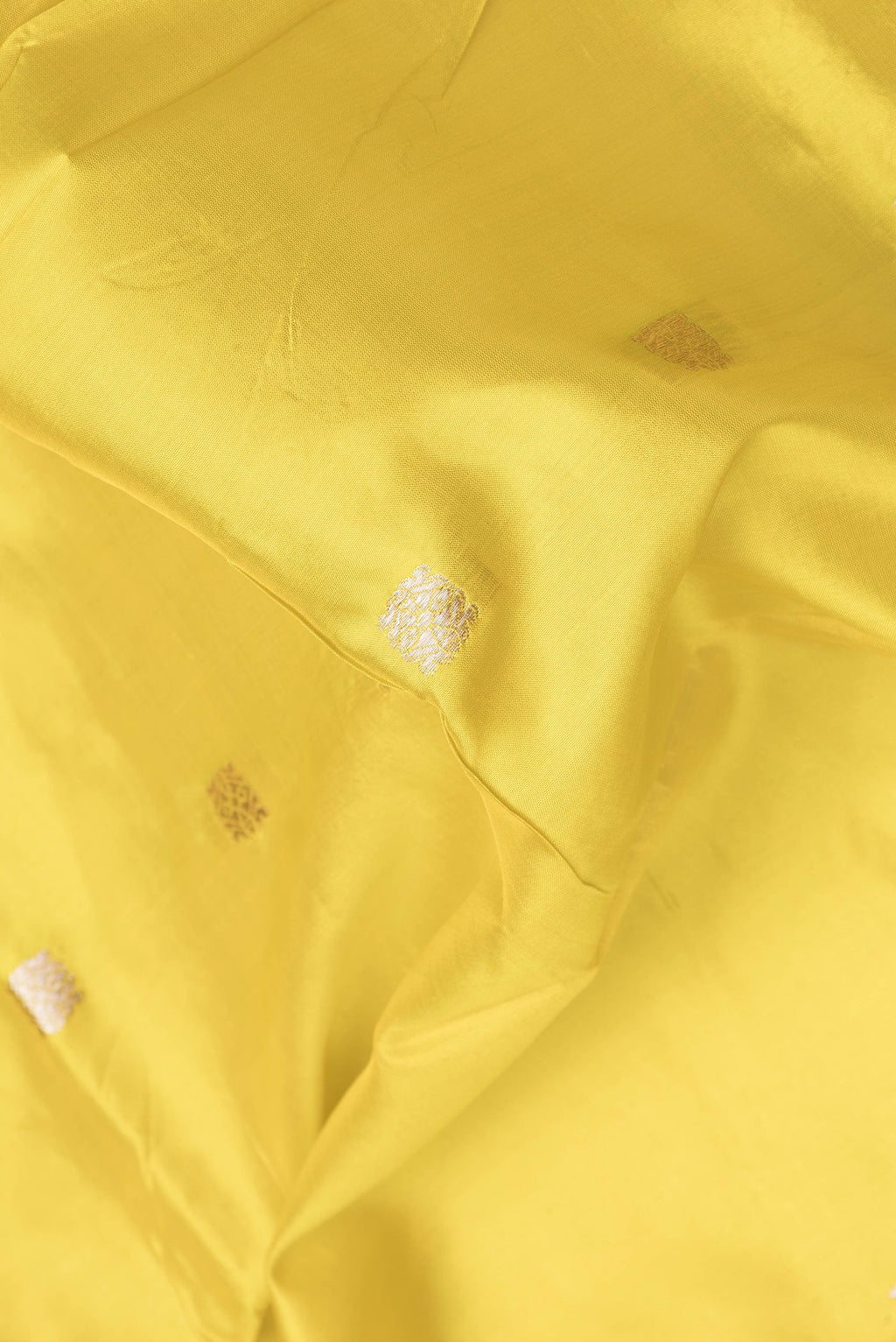 Close up of Yellow Dual Tone Banarasi Silk Saree with Zari Butta on the body and Zari Border.  displaying folds