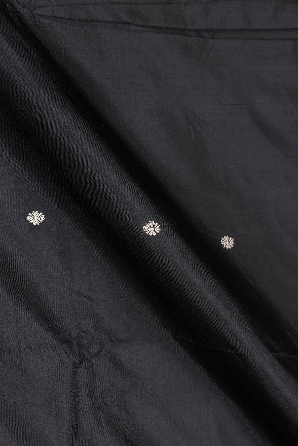 Close up of Black Dual Tone Banarasi Silk Saree with Zari Butta on the body and Zari Border displaying folds