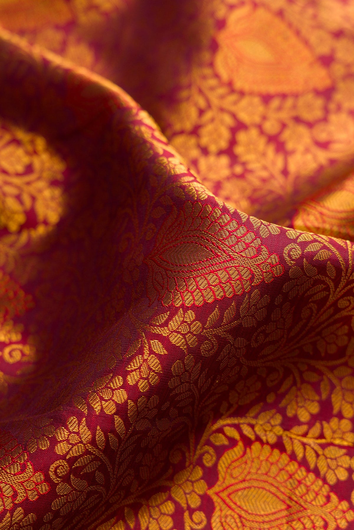 Close up of Maroon Dual Tone Kanjivaram Silk Saree with Zari Brocade on the body and Zari Border.  displaying folds