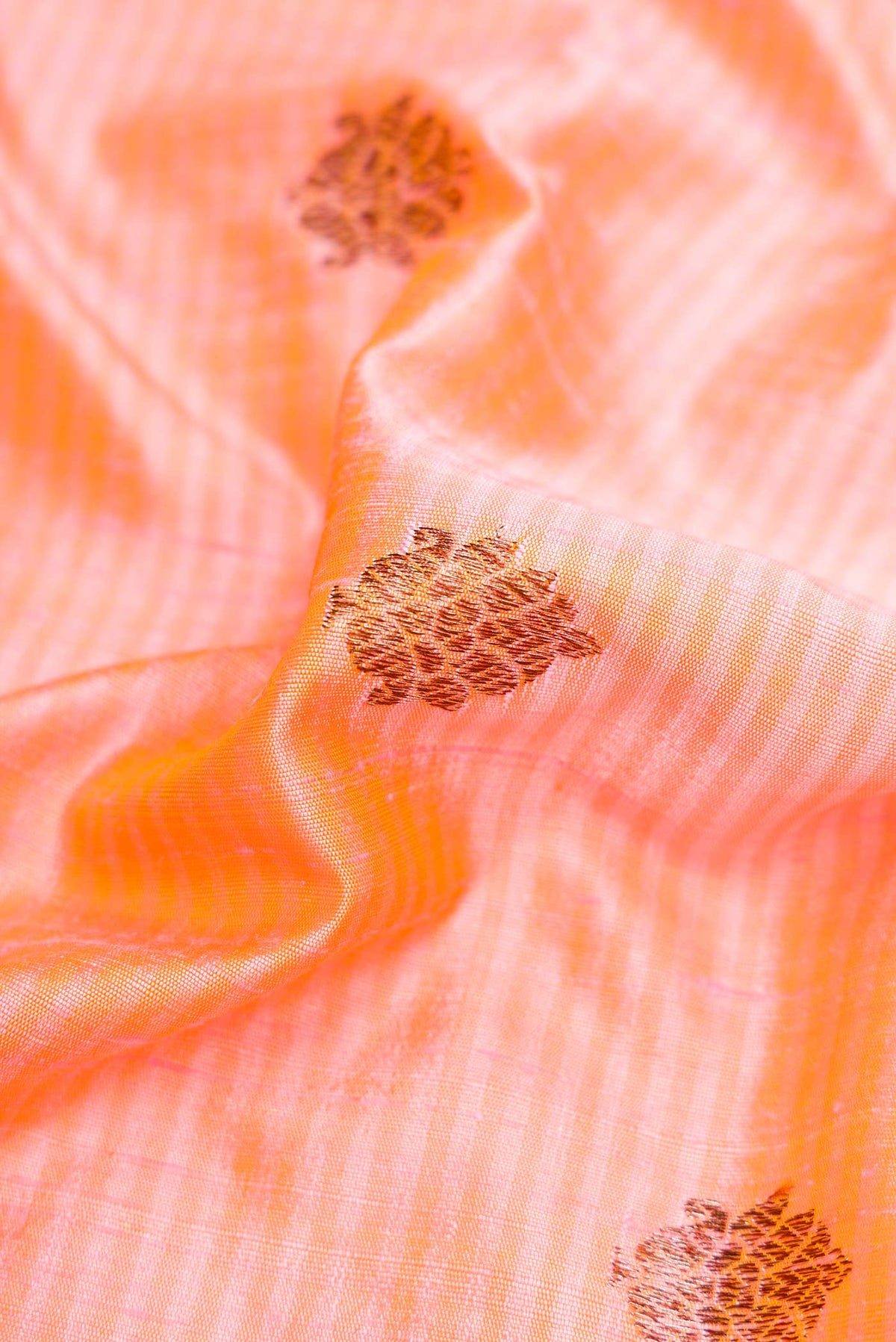 Close up of Peach Banarasi Tussar Silk Saree with Zari And Thread Butta on the body and Zari And Thread Border displaying folds