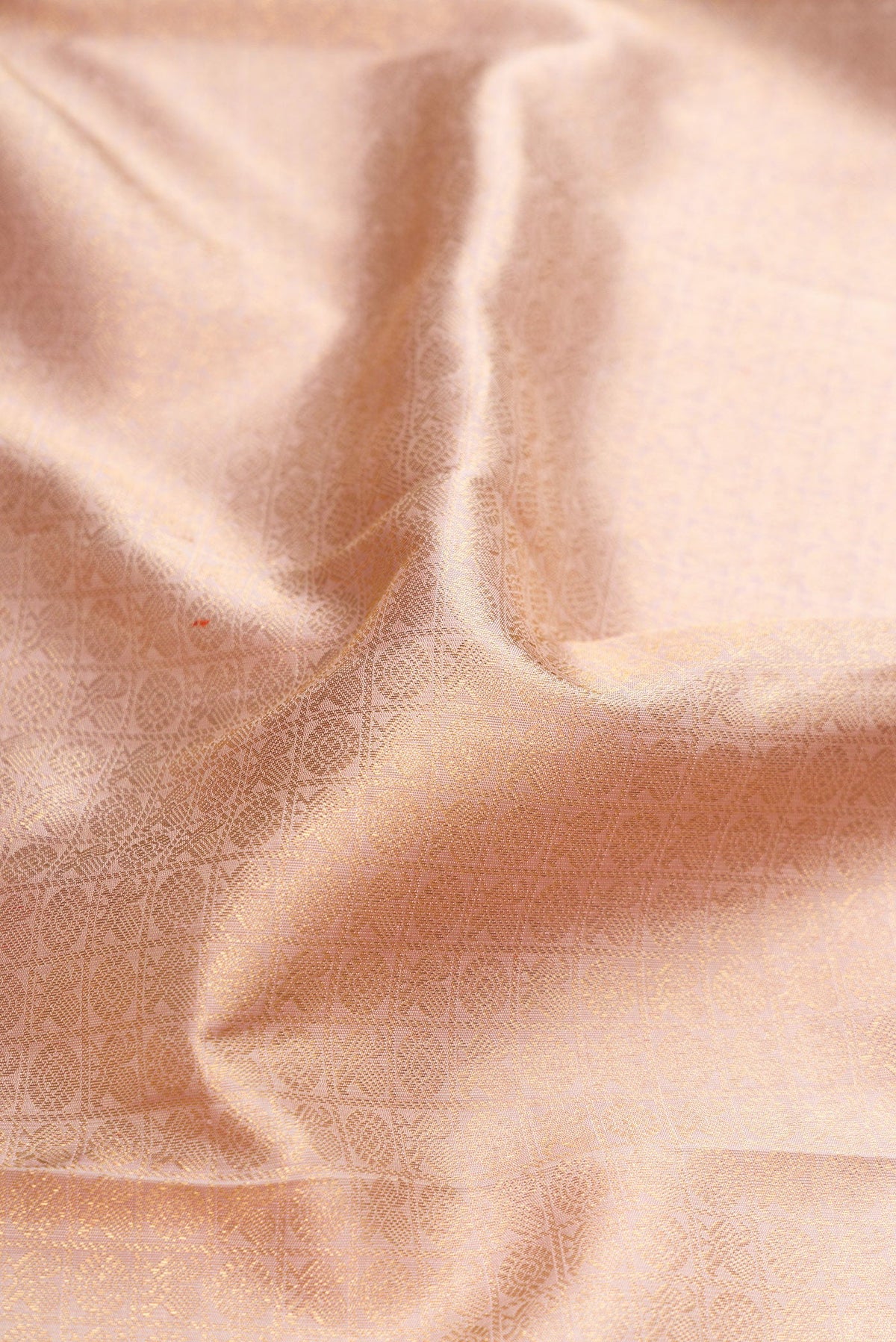 Close up of Pure Silk Pure Zari Rose Gold Dual Tone Kanjivaram Saree with Zari Brocade on the body and Zari Border.  displaying folds