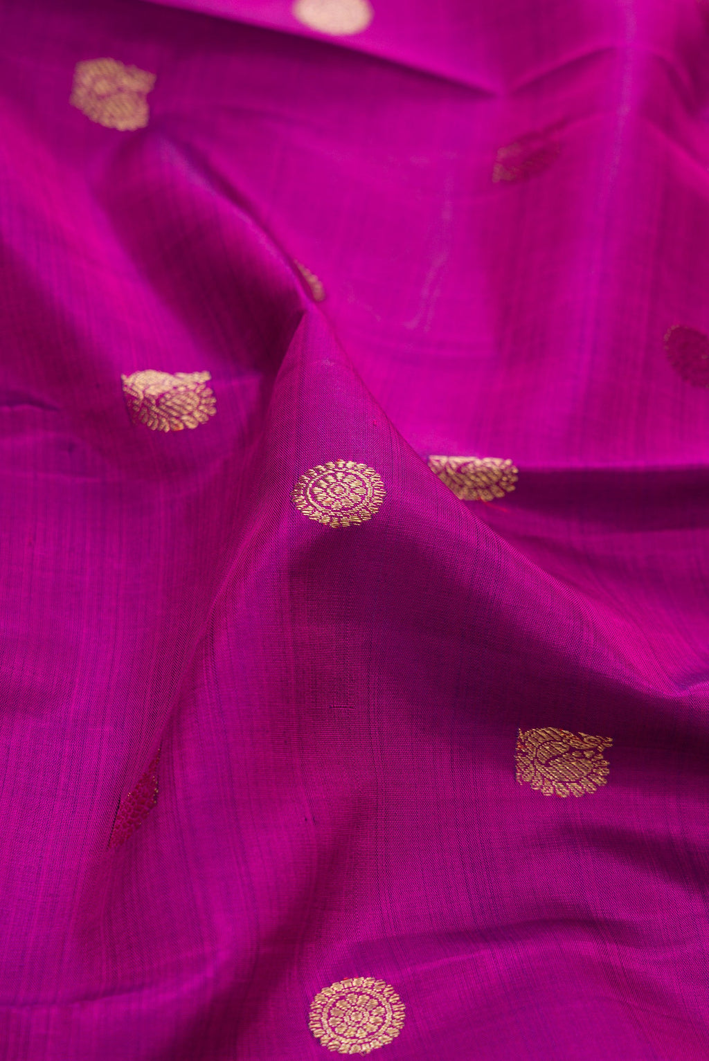 Close up of Pure Silk Pure Zari Magenta Dual Tone Kanchipuram Saree with Zari Butta on the body and Zari Border.  displaying folds