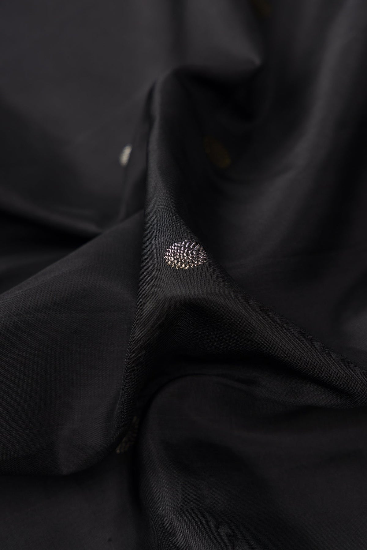 Close up of Black Dual Tone Kanjivaram Silk Saree with Zari Butta on the body and Temple Border.  displaying folds