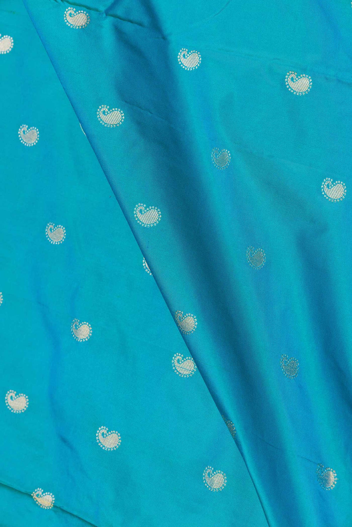 Close up of Sky Blue Dual Tone Paithani Silk Saree with Zari Butta on the body and Paithani Border displaying folds