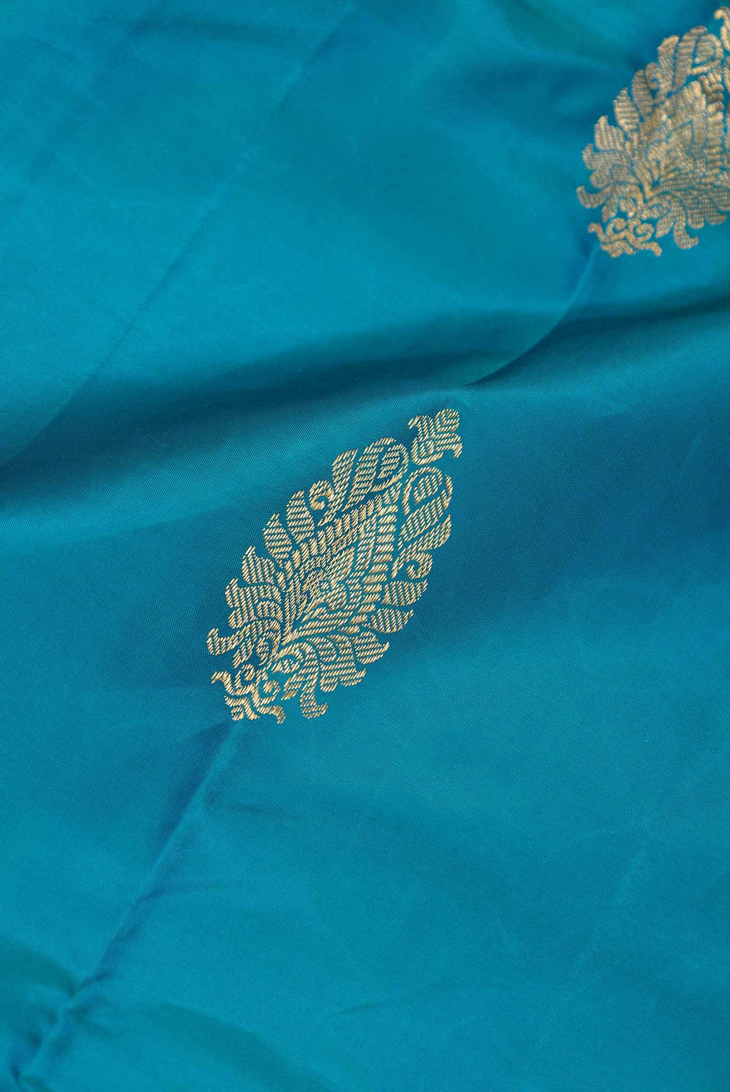 Close up of Peacock Blue Dual Tone Kanchipuram Saree with Zari Butta on the body and Zari Border displaying folds