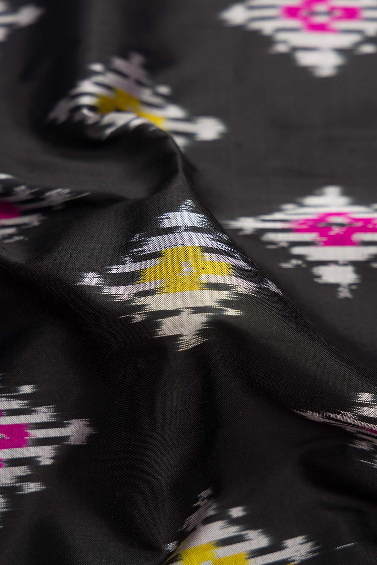 Close up of Black Dual Tone Double Ikat Saree with Ikat Print on the body and Ikat Border.  displaying folds