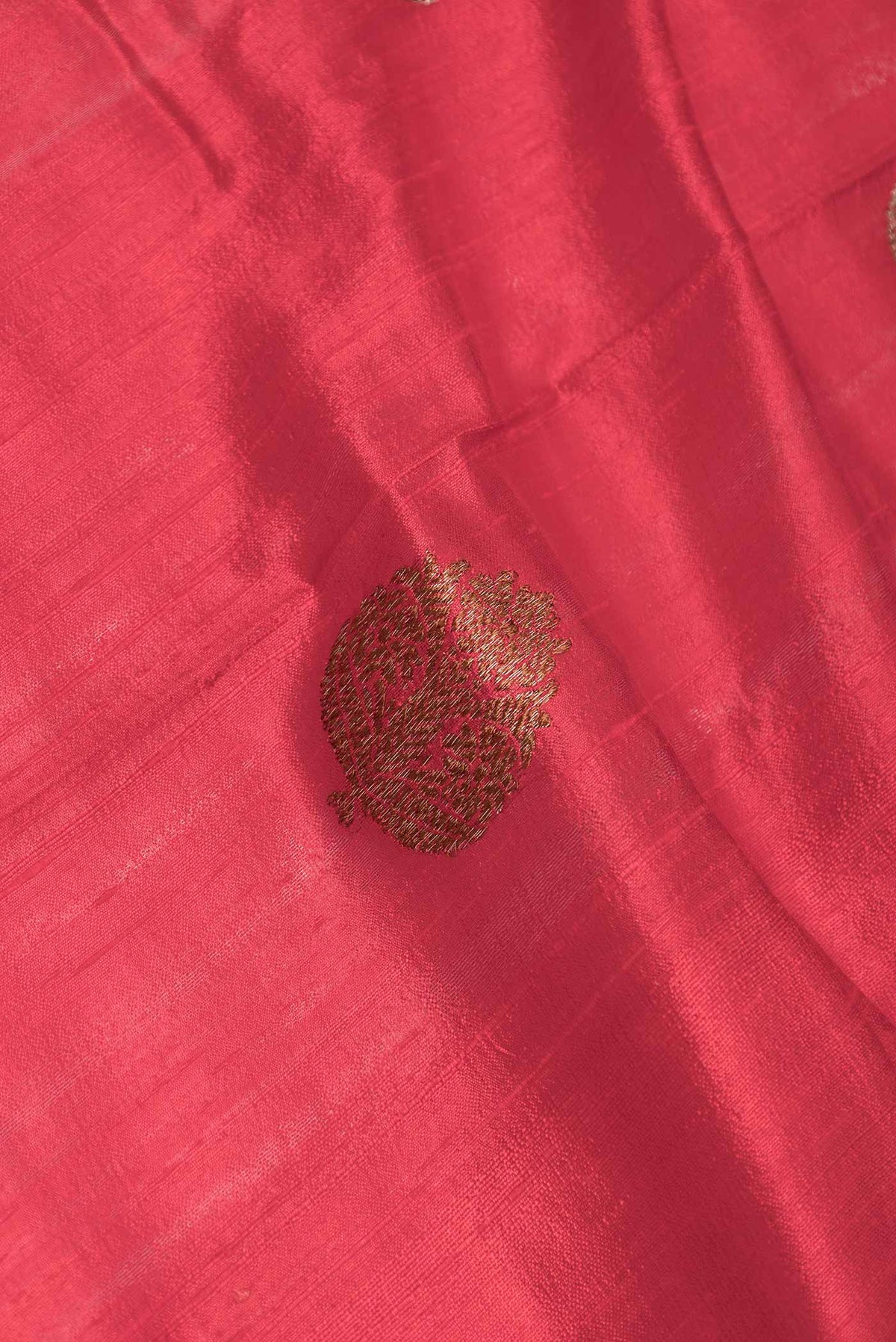 Close up of Red Dual Tone Raw Silk Saree with Zari Butta on the body and Zari Border displaying folds