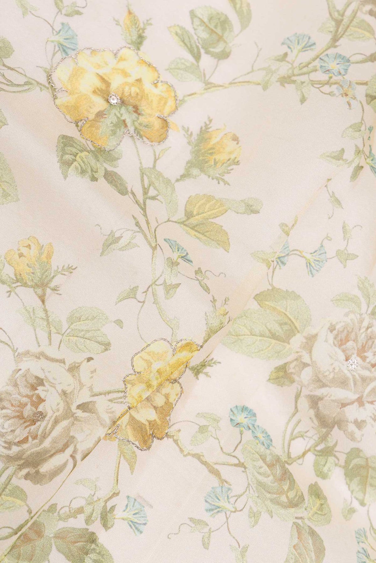 Close up of Cream Organza Silk Saree with Floral Print on the body and Embroidery Border displaying folds