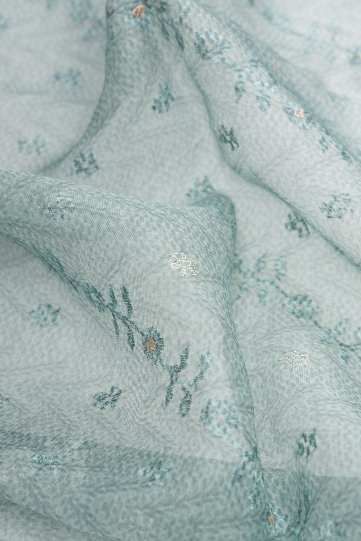 Close up of Blue Dual Tone Organza Silk Saree with Printed design on the body and Embroidery Border.  displaying folds