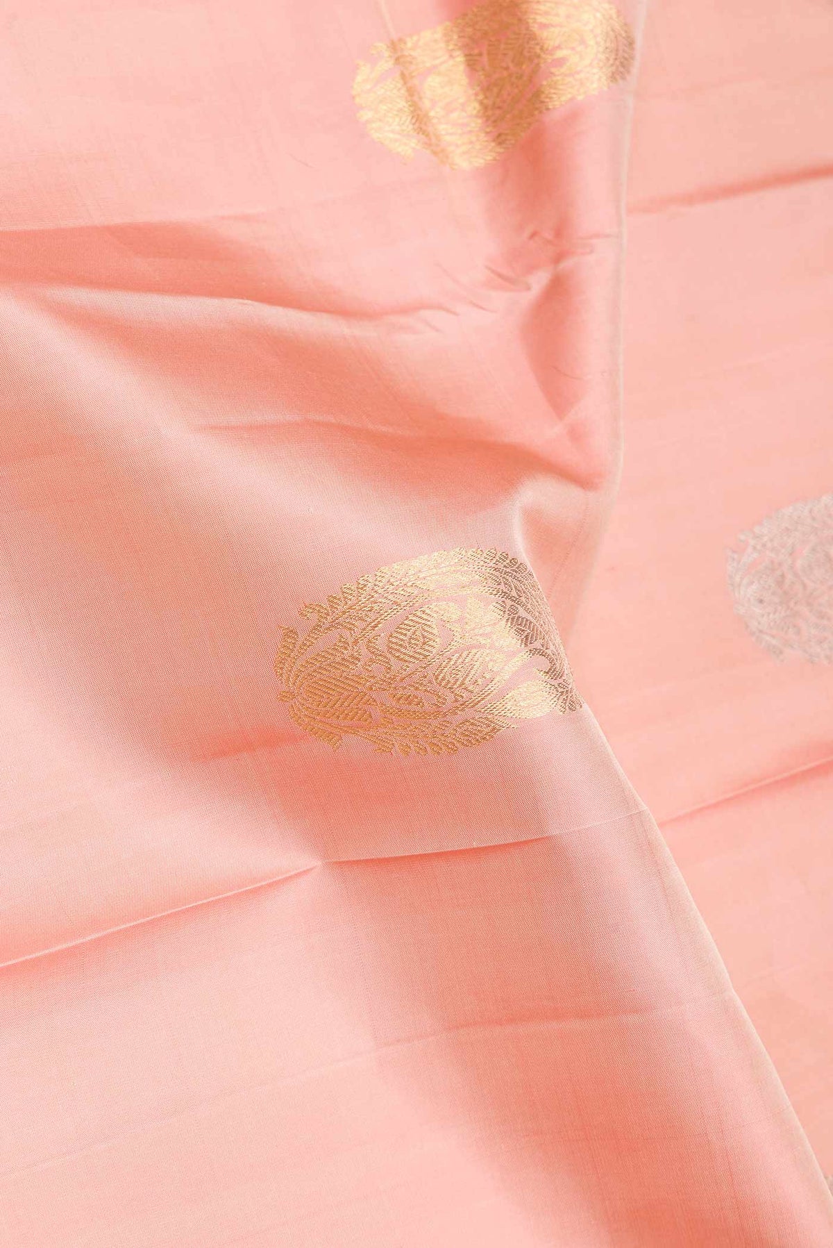 Close up of Golden Peach Dual Tone Kanjivaram Saree with Zari Butta on the body and Zari Border.  displaying folds