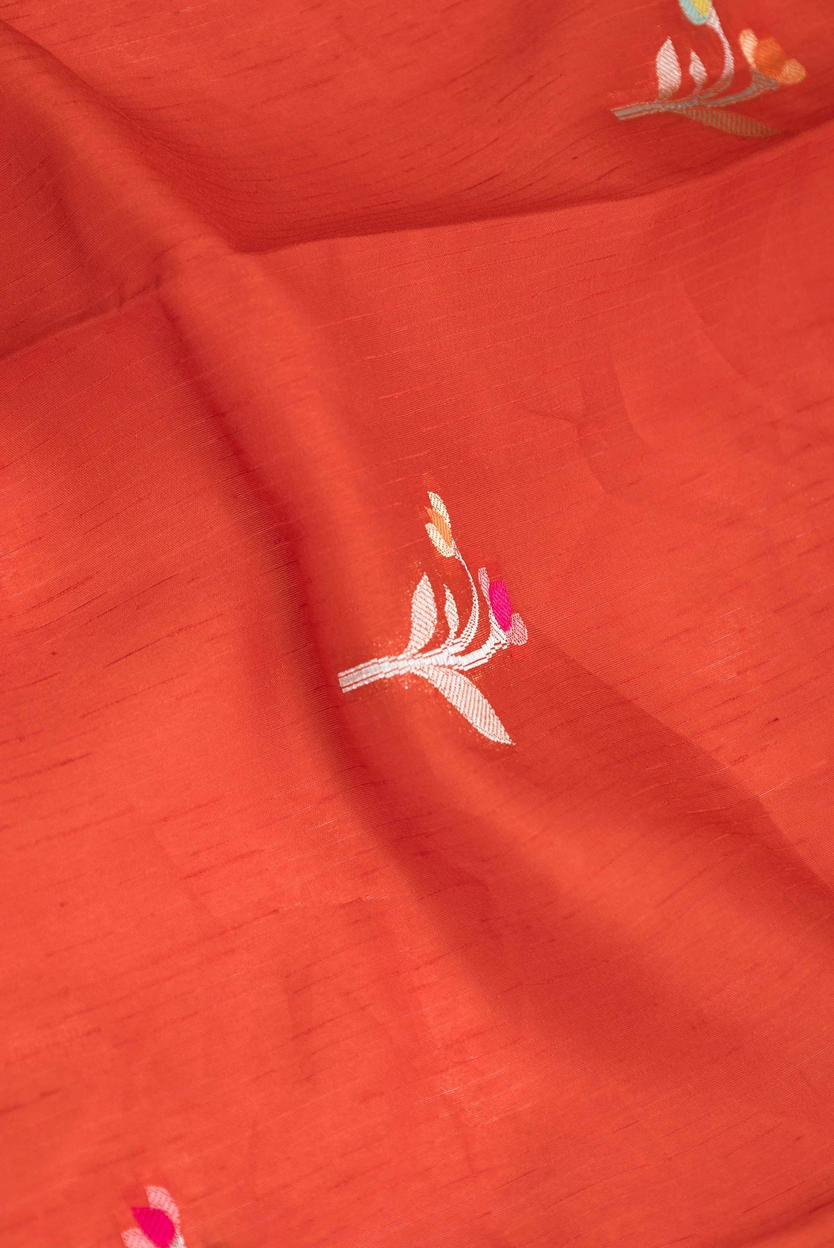 Close up of Red Banarasi Raw Silk Saree with Zari And Thread Butta on the body and Zari Border displaying folds