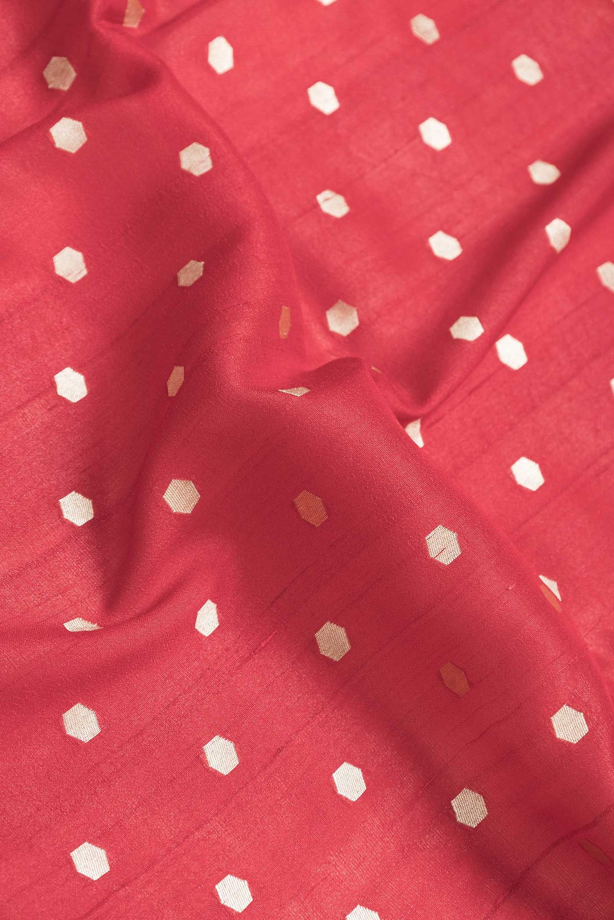 Close up of Red Dual Tone Tussar Saree with Zari Butta on the body and Fancy Border.  displaying folds
