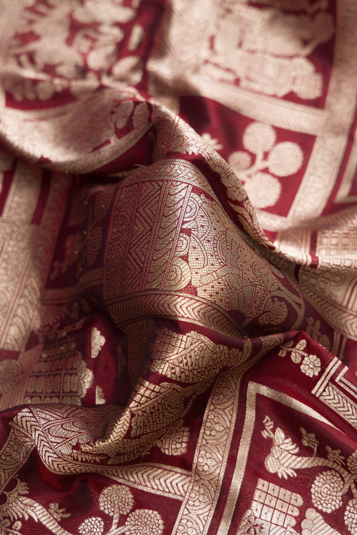 Close up of Maroon Dual Tone Banarasi Silk Saree with Zari Brocade on the body and Zari Border.  displaying folds