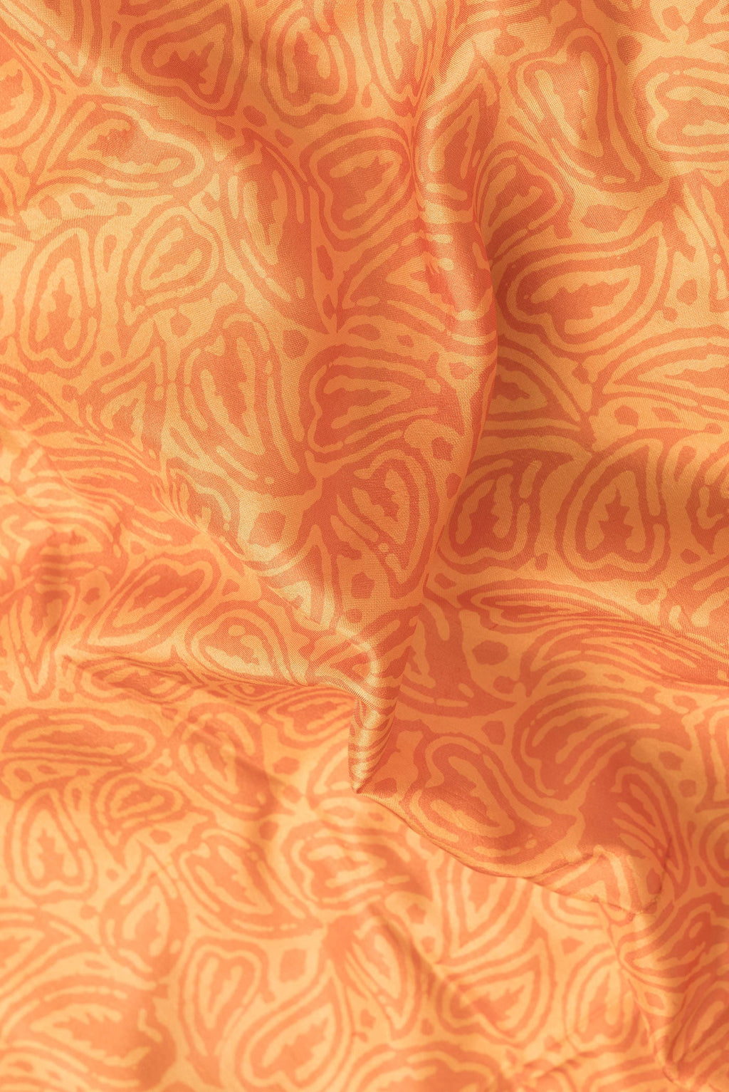 Close up of Orange Dual Tone Printed Silk Saree with Printed design on the body and Printed Border.  displaying folds