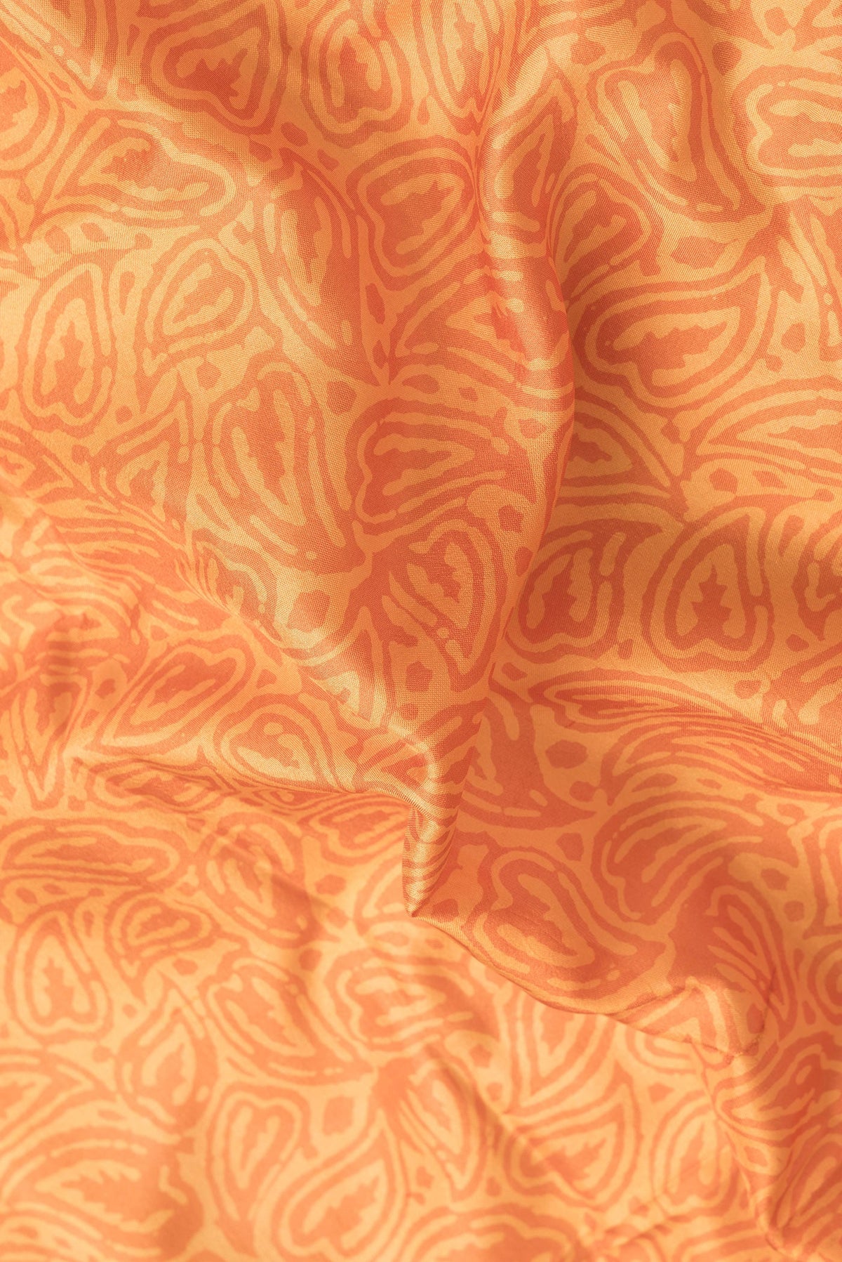 Close up of Orange Dual Tone Printed Silk Saree with Printed design on the body and Printed Border.  displaying folds