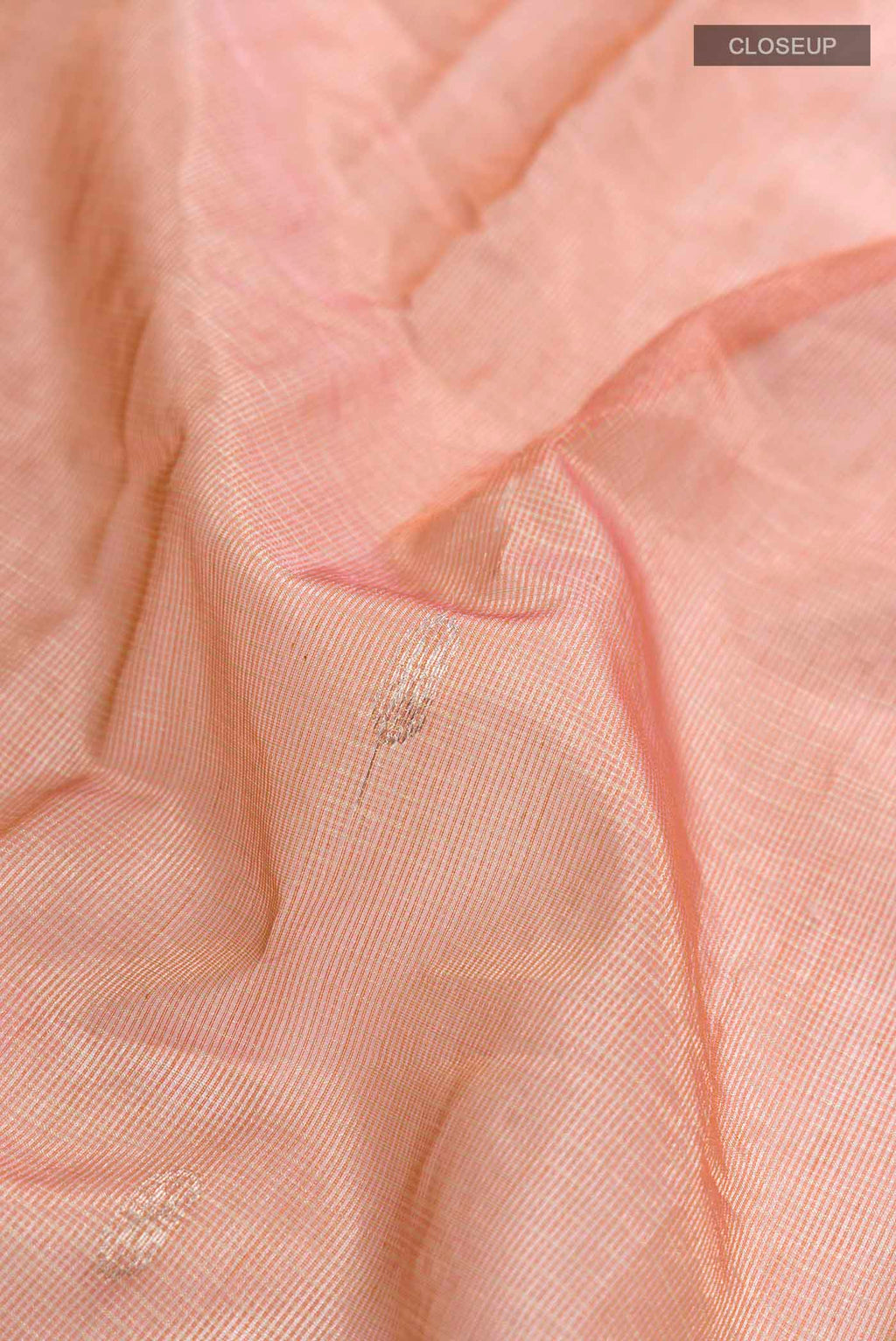 Close up of Peach Maheshwari Silk Cotton Saree with Zari Butta on the body and Zari Border displaying folds