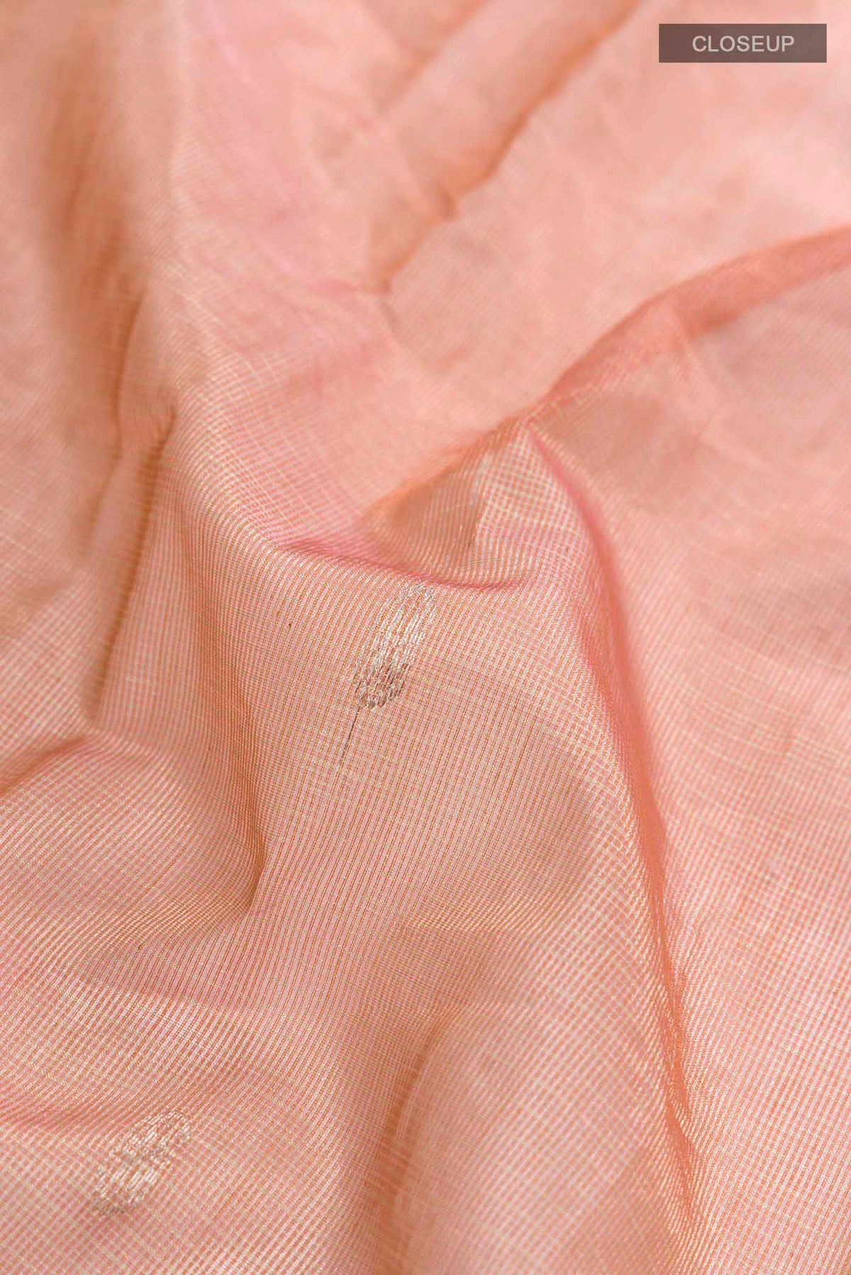 Close up of Peach Maheshwari Silk Cotton Saree with Zari Butta on the body and Zari Border displaying folds