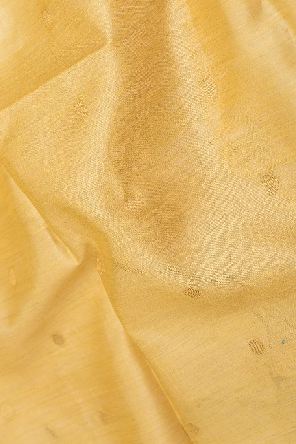 Close up of Mustard Dual Tone Tussar Saree with Zari Butta on the body and Zari Border displaying folds