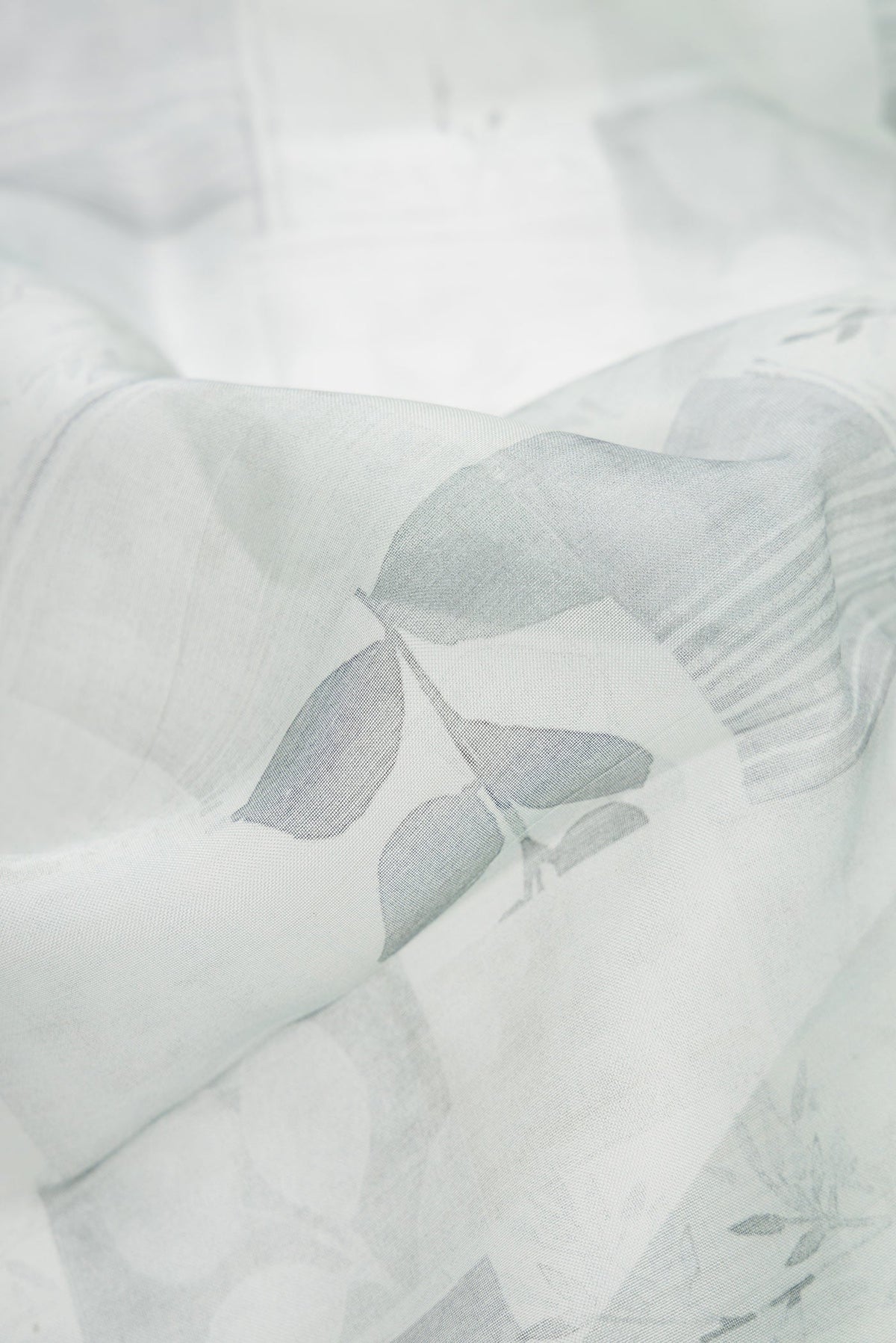 Close up of Grey Dual Tone Organza Silk Saree with Printed design on the body and Zari Border.  displaying folds