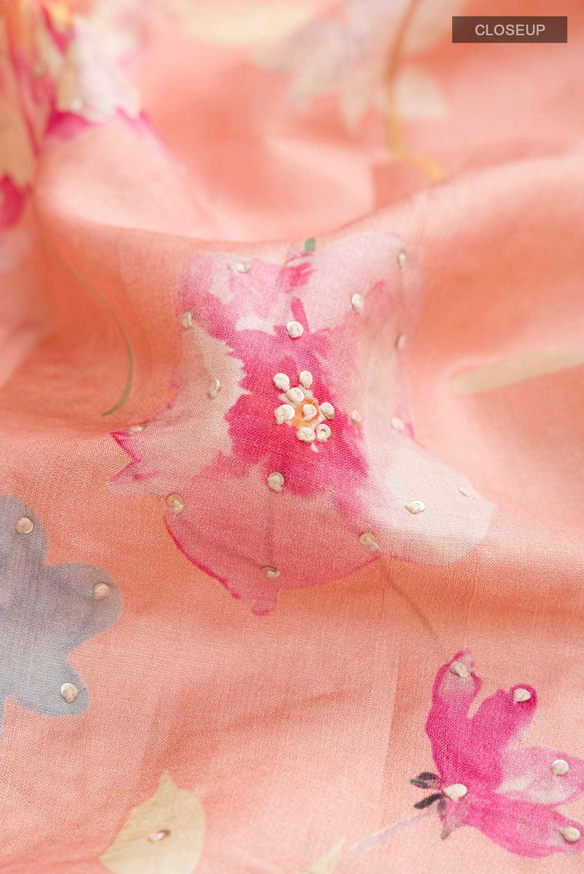 Close up of Peach Bhagalpuri Tussar Silk Saree with Printed design on the body and Zari Border displaying folds