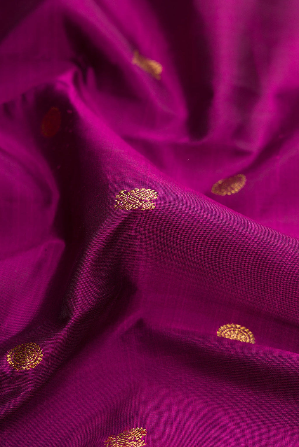 Close up of Pure Silk Pure Zari Magenta Dual Tone Kanjivaram Saree with Zari Butta on the body and Zari Border.  displaying folds