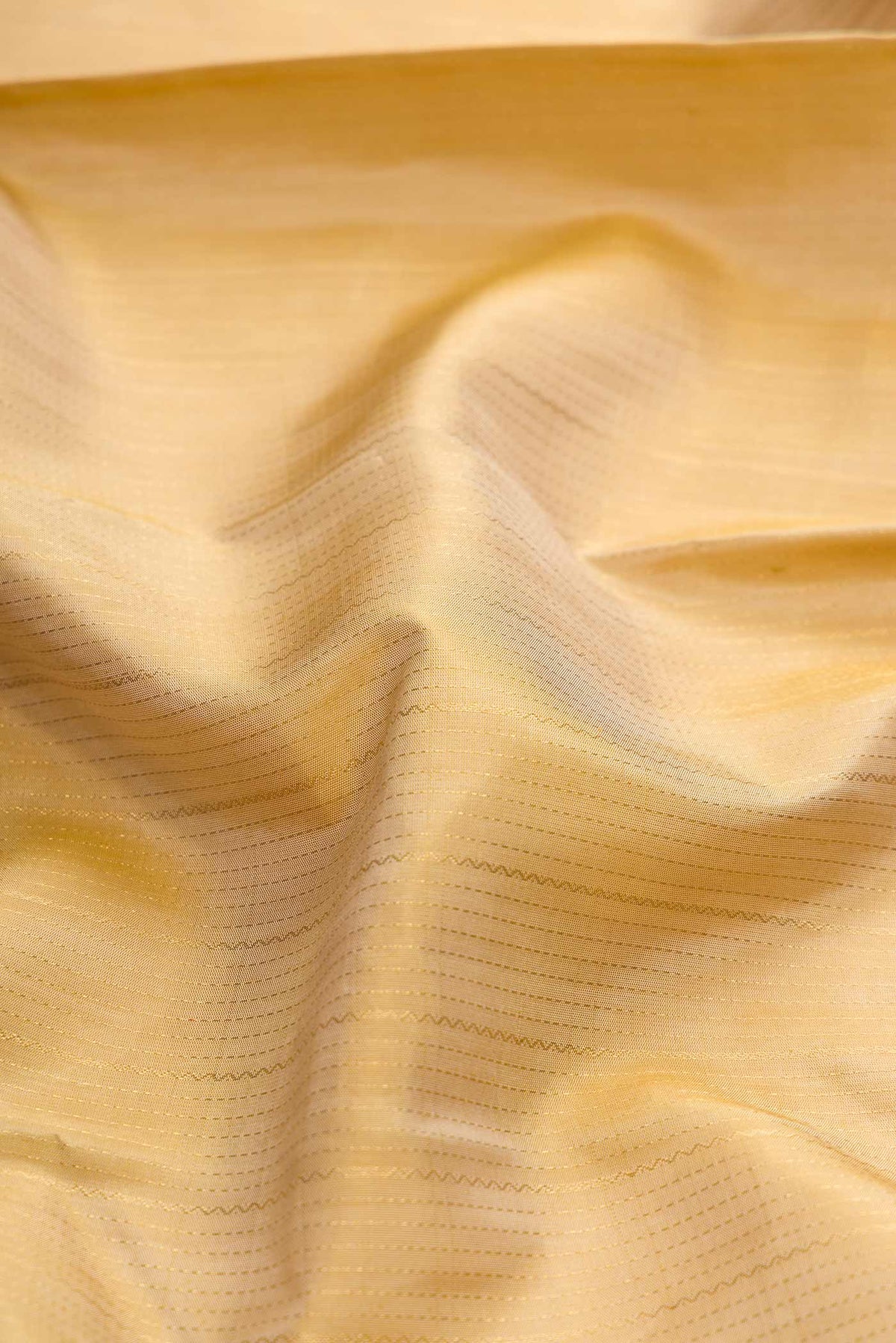 Close up of Beige Dual Tone Kanchipuram Silk Saree with Stripes on the body and Zari Border displaying folds