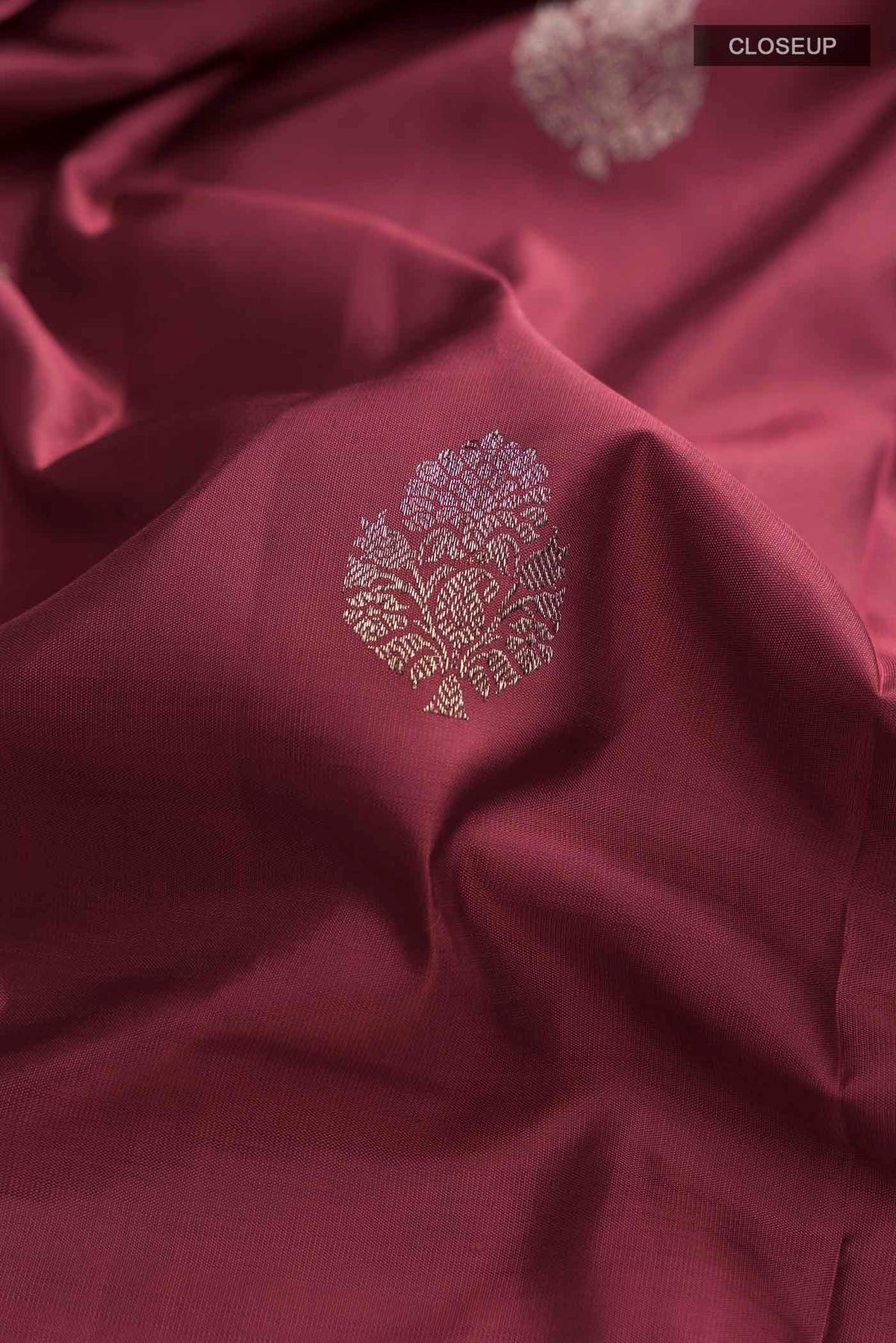 Close up of Maroon Kanchipuram Silk Saree with Zari Butta on the body and Zari Border displaying folds