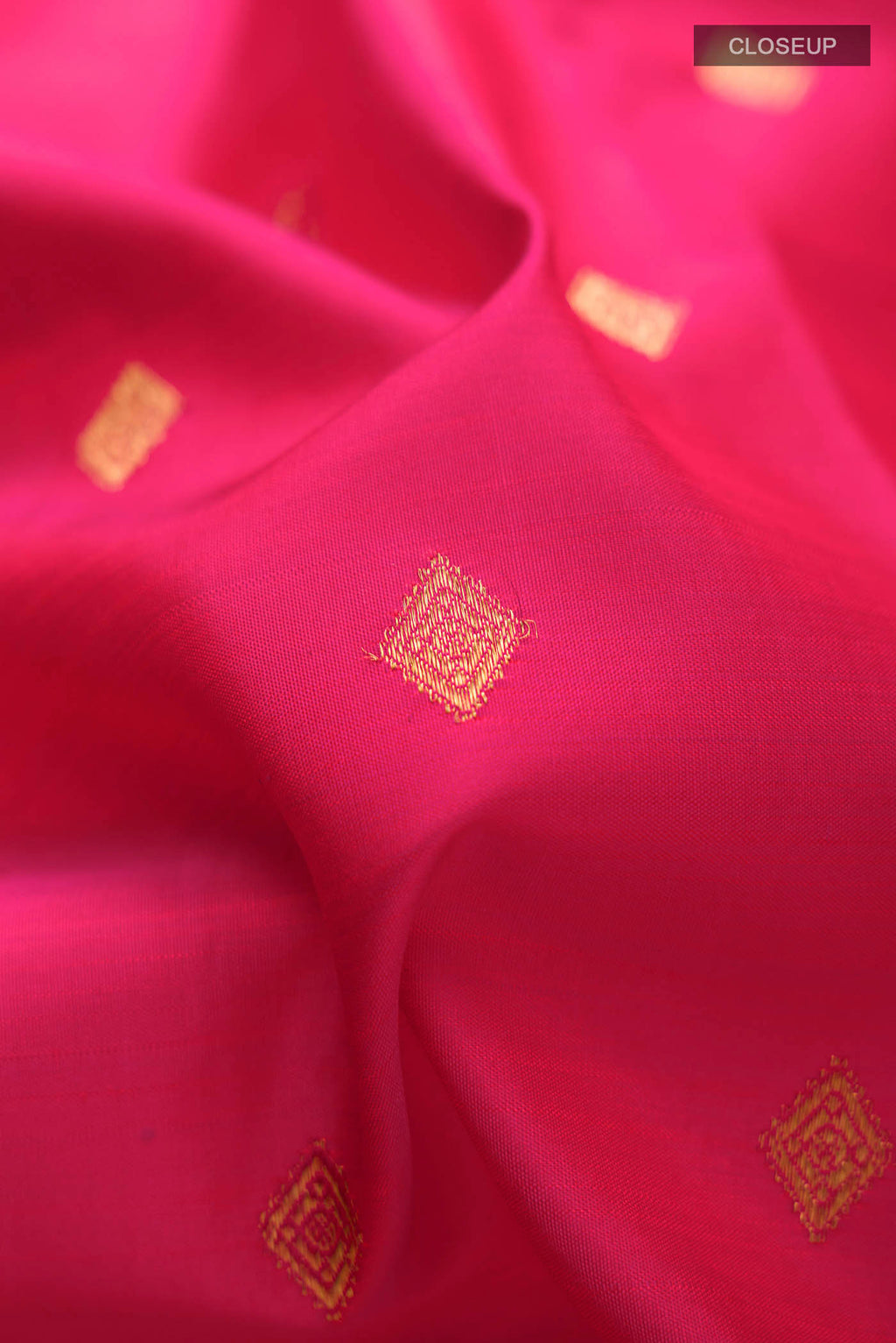 Close up of Pink Kanchipuram Silk Saree with Zari Butta on the body and Zari Border displaying folds
