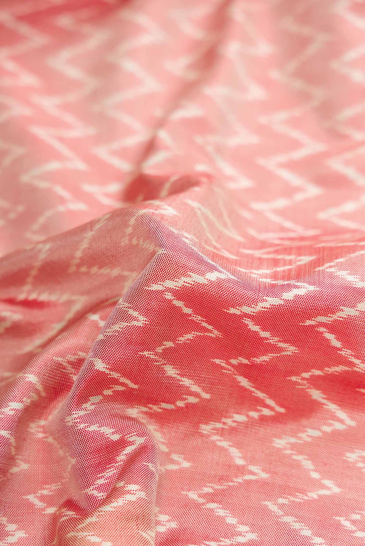 Close up of Coral Pochampally Silk Saree with Pure Ikat on the body and Zari Border displaying folds