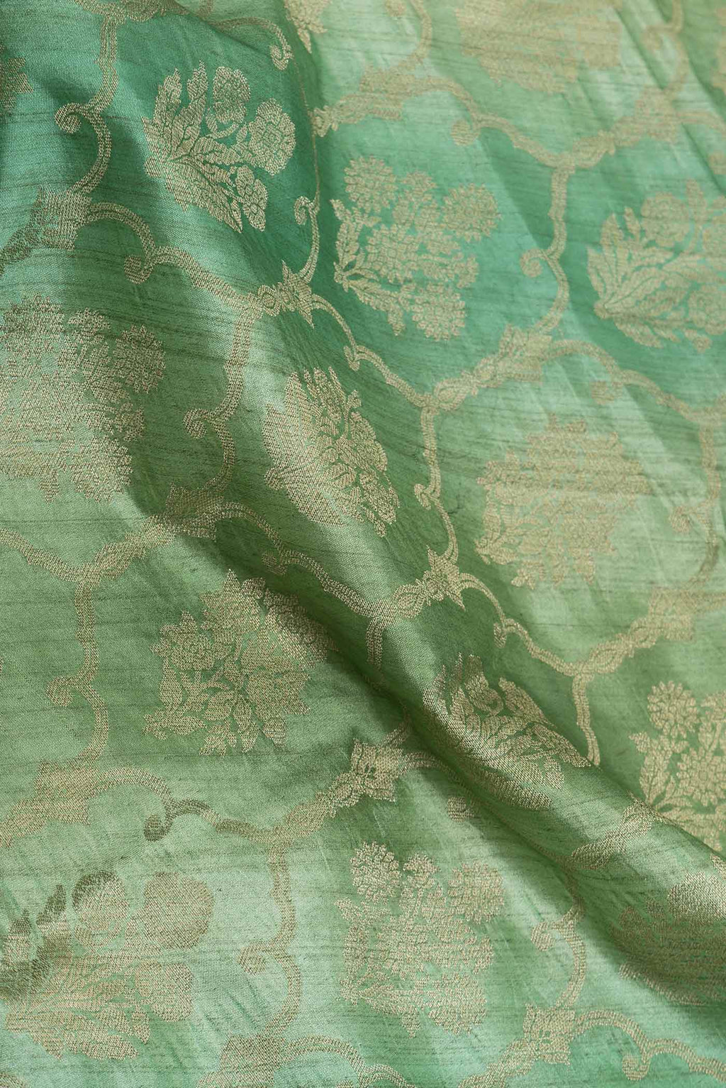 Close up of Sage Green Banarasi Raw Silk Saree with Zari Butta on the body and Zari Border displaying folds