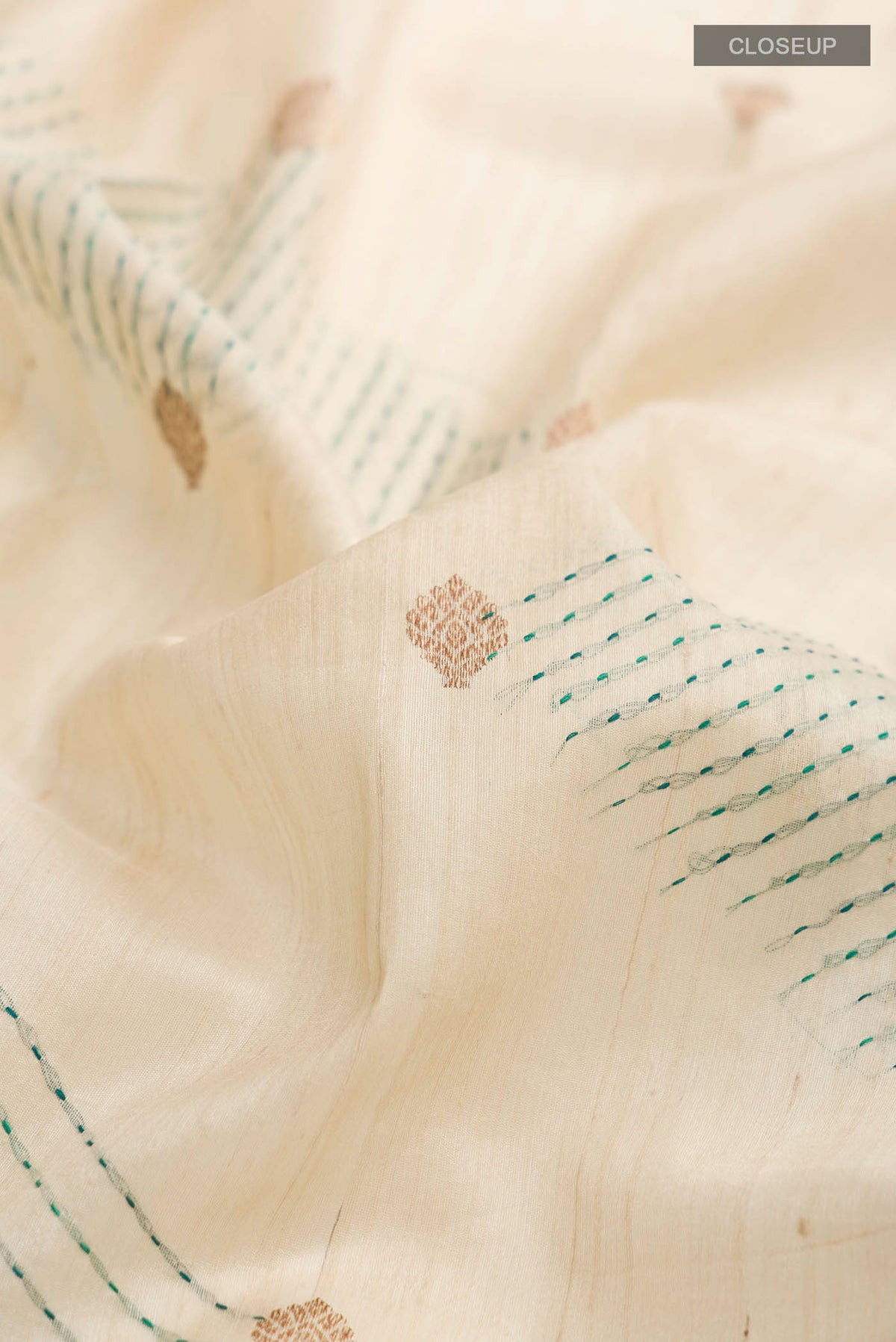 Close up of Beige Bhagalpuri Tussar Silk Saree with Zari Butta on the body and Embroidery Border displaying folds