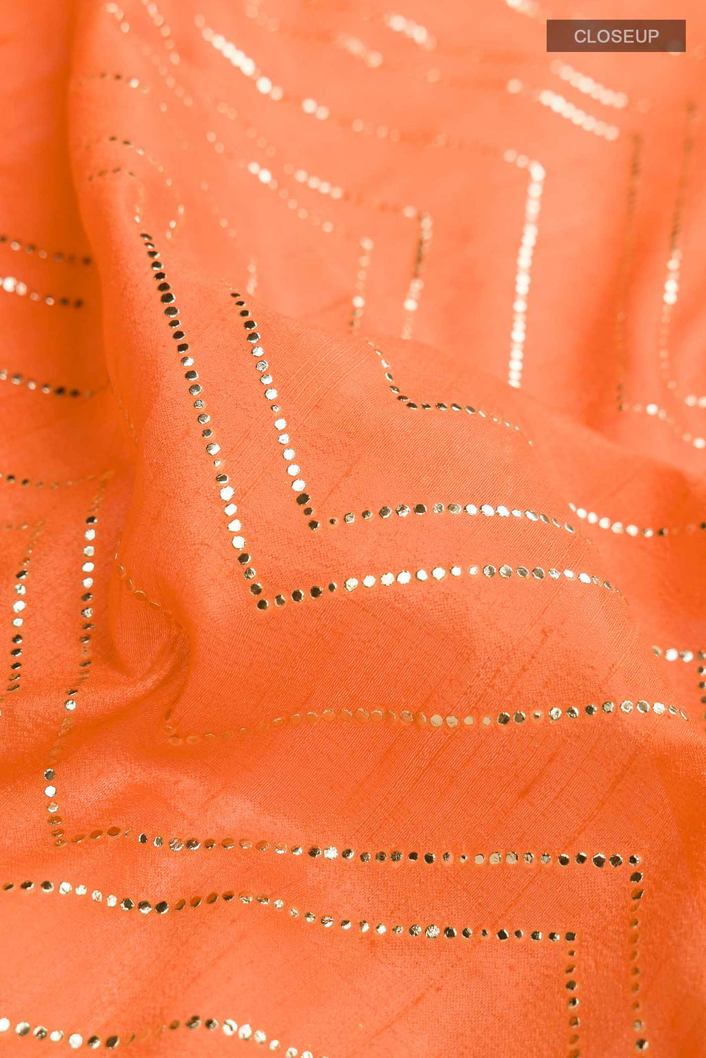 Close up of Orange Raw Silk Saree with Embroidery on the body and Zari Border displaying folds