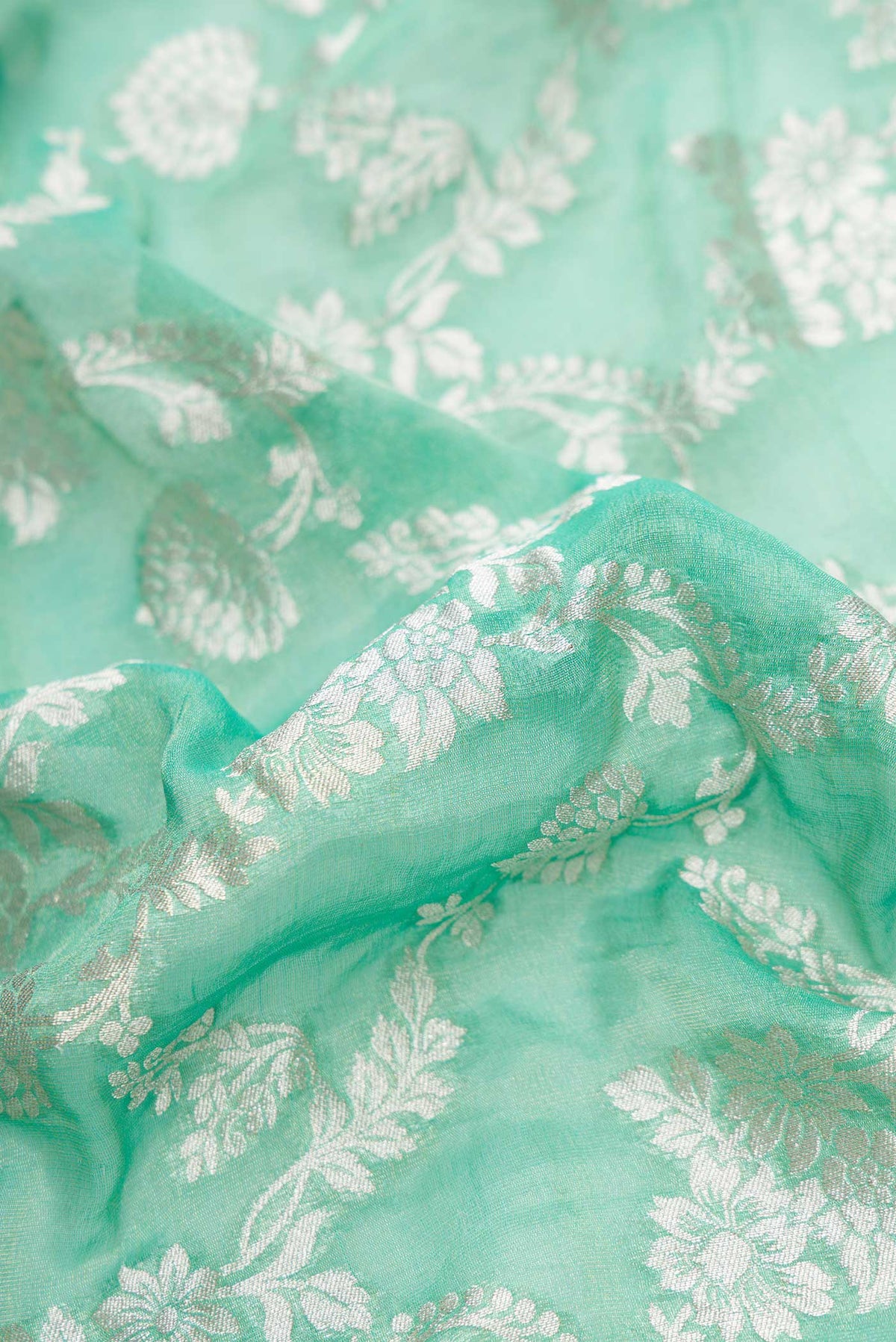 Close up of Green Dual Tone Banarasi Georgette Saree with Zari Brocade on the body and Zari Border.  displaying folds