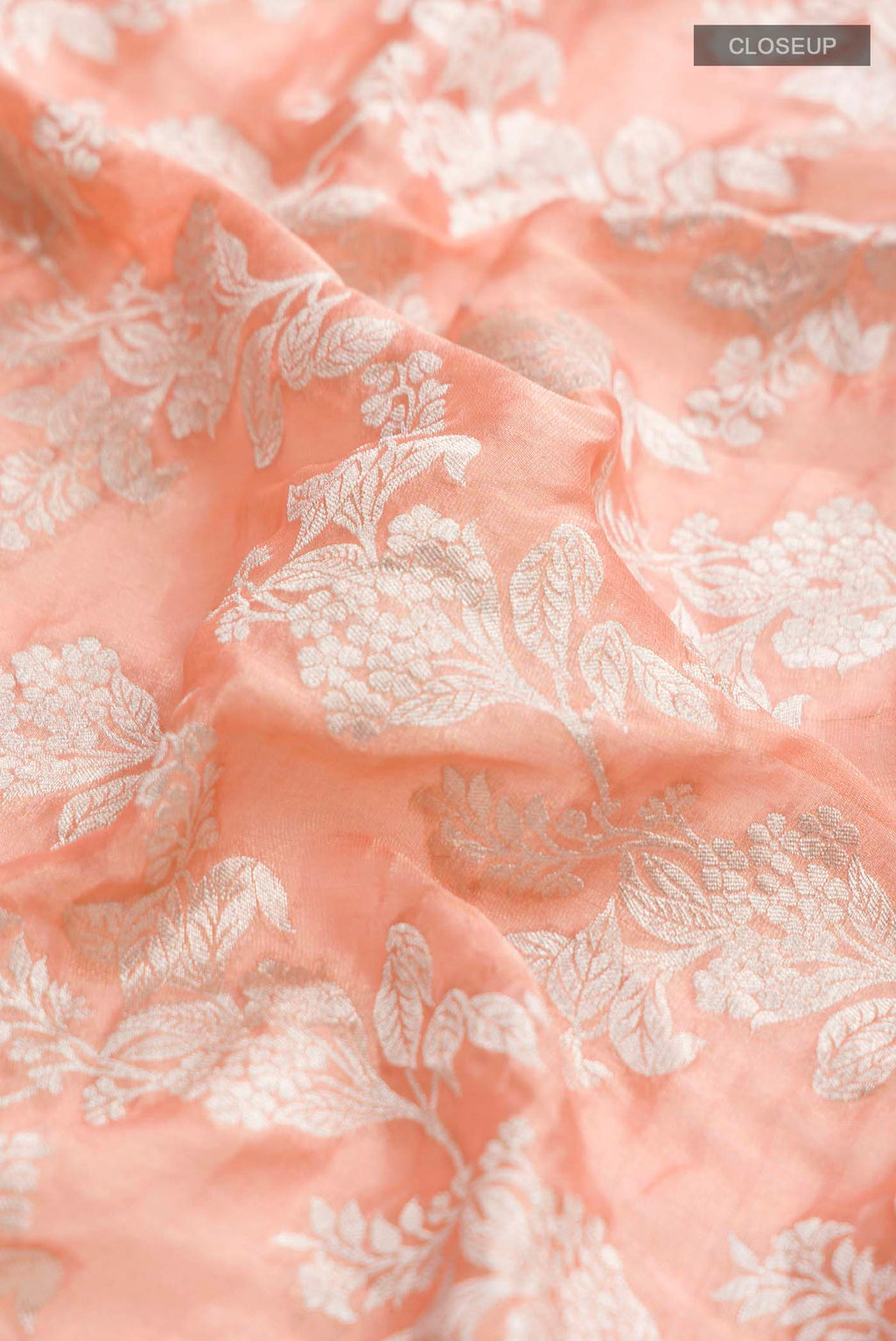 Close up of Peach Banarasi Georgette Saree with Zari Butta on the body and Zari Border displaying folds