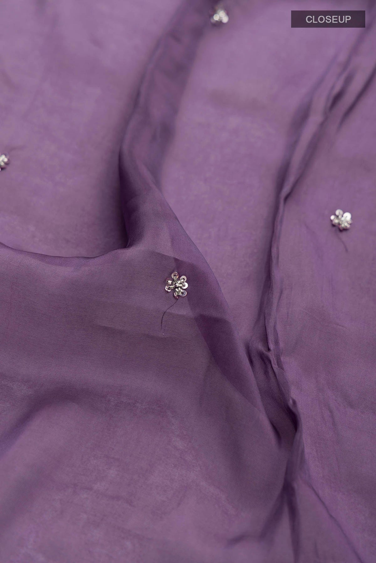 Close up of Lilac Satin Silk Saree with Plain Body and Embroidery Border displaying folds