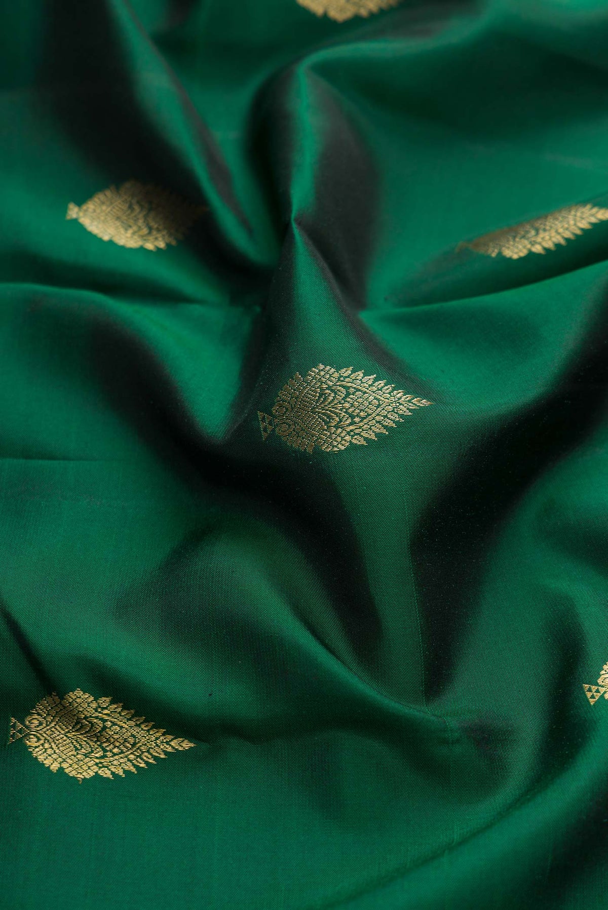 Close up of Green Dual Tone Kanchipuram Silk Saree with Zari Butta on the body and Zari Border displaying folds