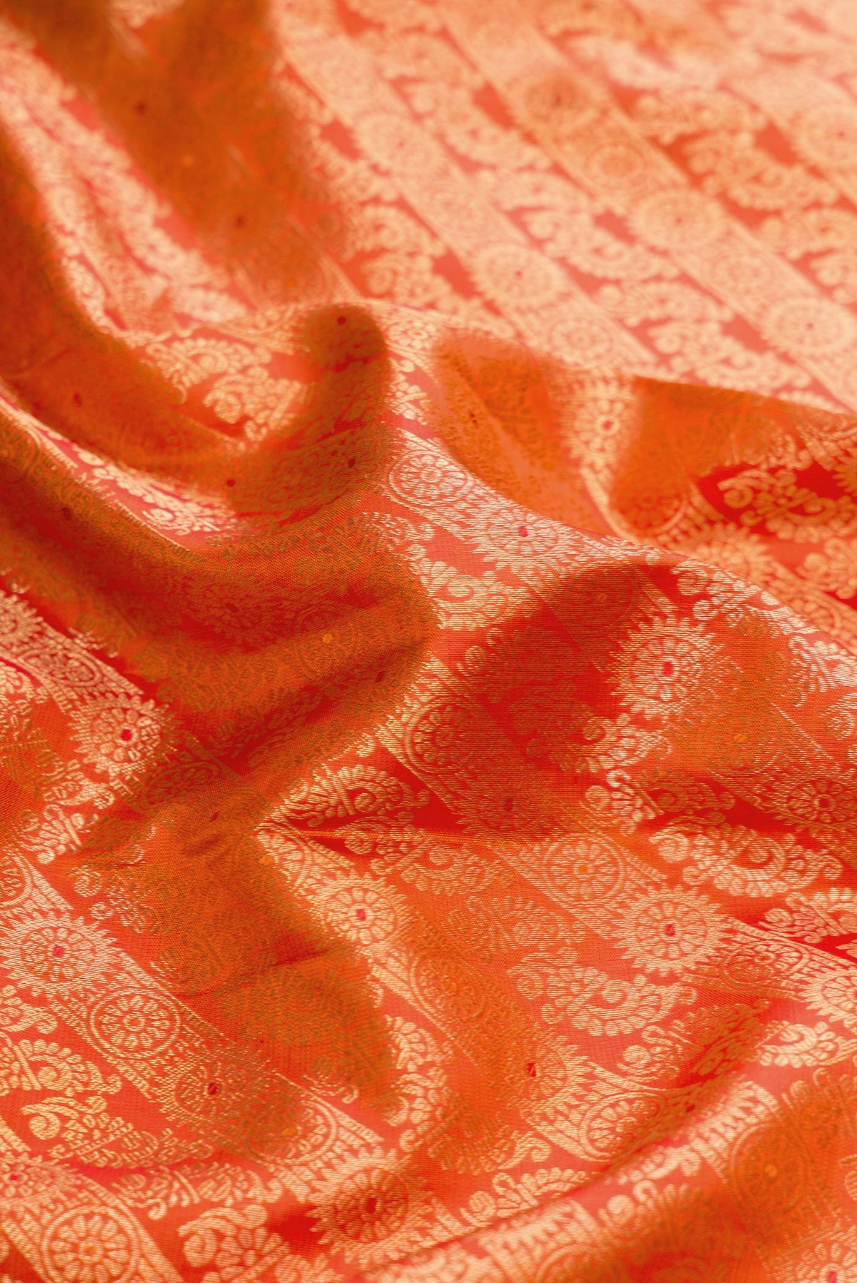 Close up of Orange Dual Tone Kanjivaram Silk Saree with Zari Brocade on the body and Zari Border.  displaying folds