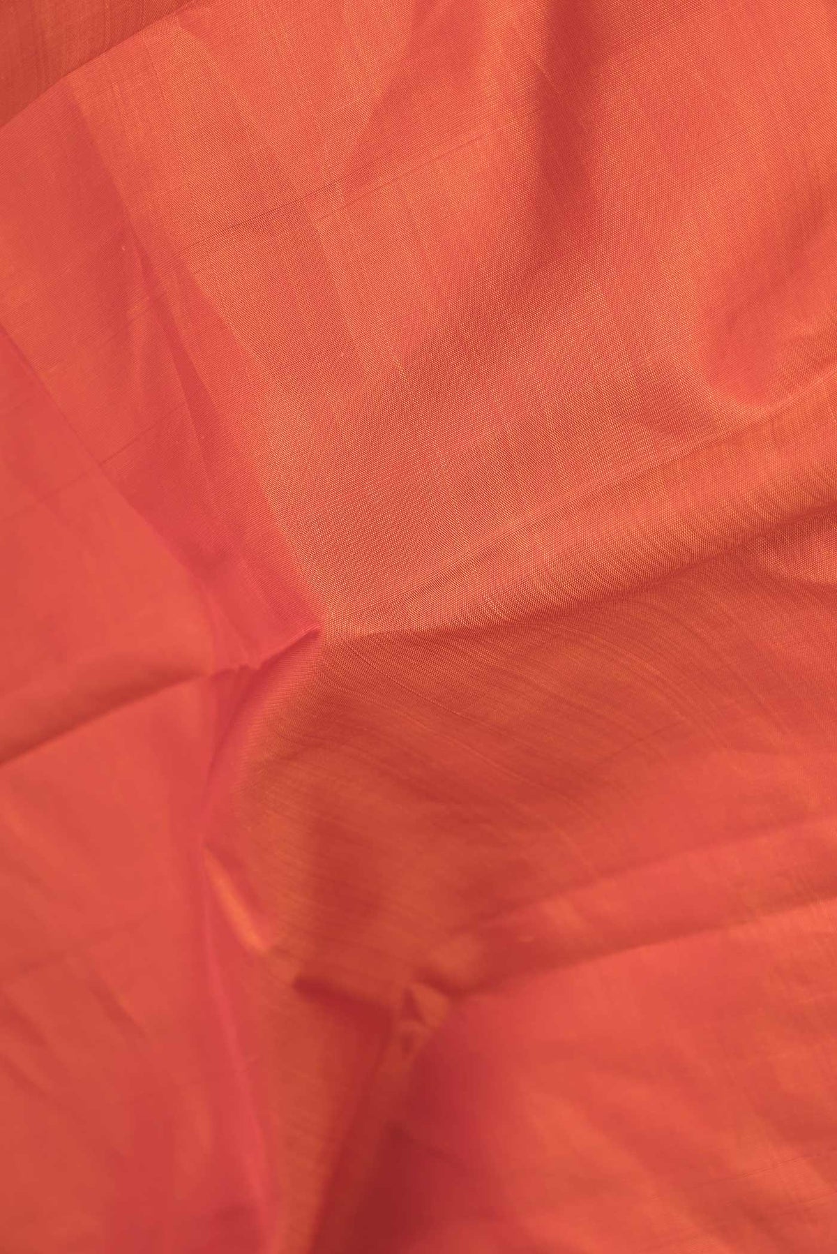 Close up of Orange Dual Tone Kanchipuram Saree with Plain Body and Zari Border displaying folds