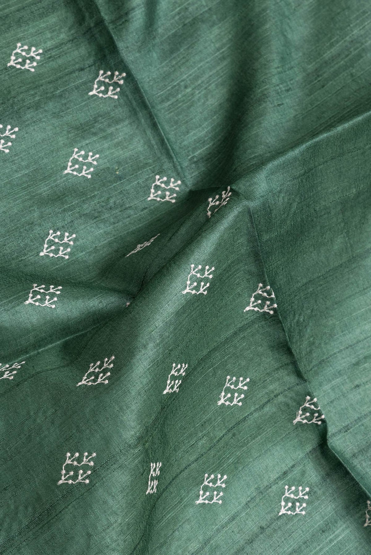 Close up of Green Dual Tone Tussar Silk Saree with Embroidery on the body and Zari Border.  displaying folds